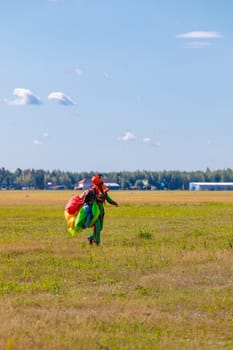 A woman skydiver walks across the field with a parachute. High quality photo