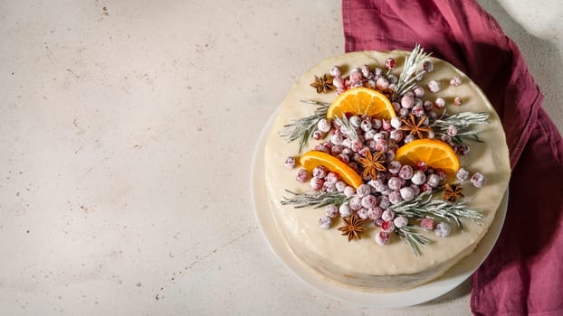 Winter homemade cake on white marble background. White cream christmas cake decored rosemary, cranberries, star anise and oranges slices. Copy space. Vertical