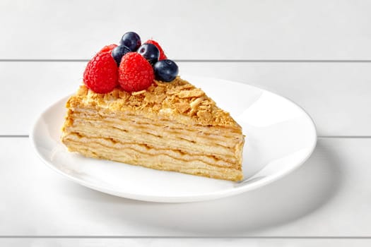 Russian style mille feuille cake Napoleon with delicate butter pastry cream topped with crumbs garnished with fresh raspberries and blueberries