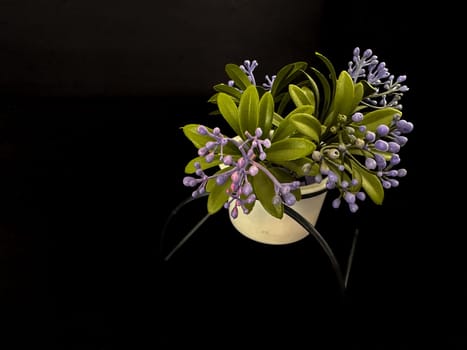 Plastic bouquet of flowers in a pot on a black background. High quality photo