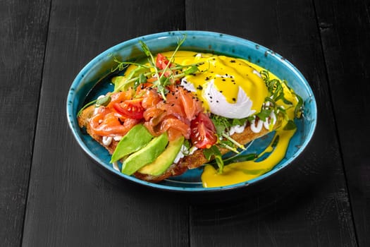 Delicious Belgian waffle topped with avocado slices, salty salmon fillet, poached egg, fresh tomatoes and fragrant greens dressed with cheese sauce. Mediterranean style brunch