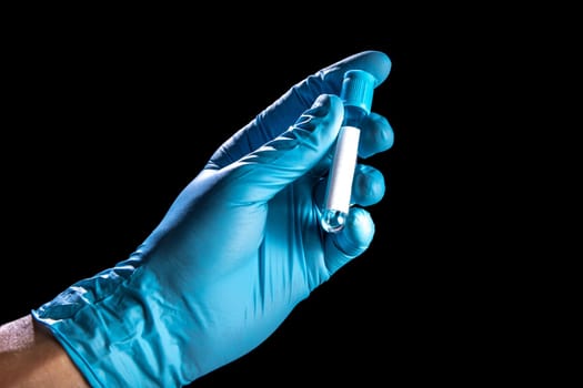 A hand in a medical blue rubber glove holds a blood test tube on a black background.