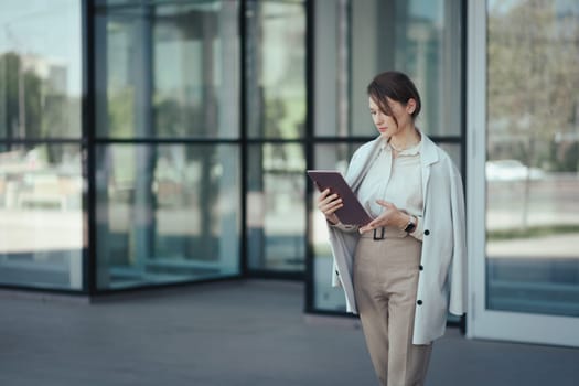 Portrait of a caucasian successful business woman used digital tablet in front of modern office building.