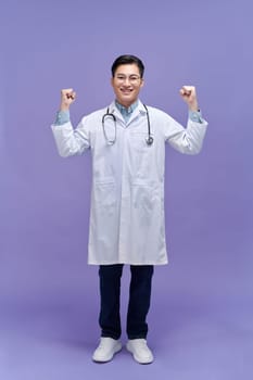 Smiling young doctor in white uniform looking at camera and pointing back