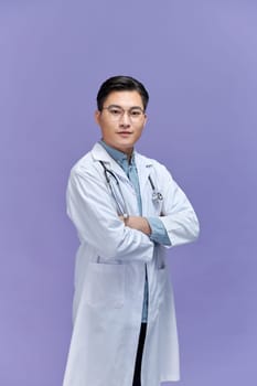 Doctor posing with arms crossed, medical staff working on purple background.