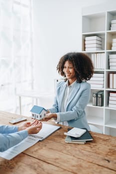 Female African american Real estate company to buy houses and land are delivering keys and houses to customers after agreeing to make a home purchase agreement and make a loan agreement