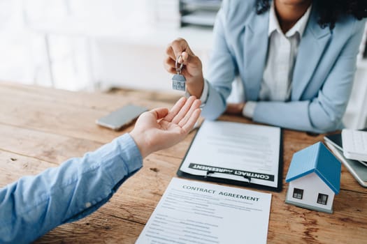 Female African american Real estate company to buy houses and land are delivering keys and houses to customers after agreeing to make a home purchase agreement and make a loan agreement