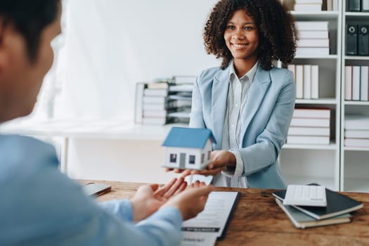 Female African american Real estate company to buy houses and land are delivering keys and houses to customers after agreeing to make a home purchase agreement and make a loan agreement