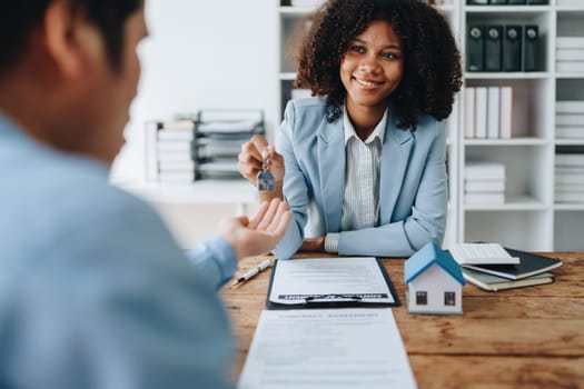 Female African american Real estate company to buy houses and land are delivering keys and houses to customers after agreeing to make a home purchase agreement and make a loan agreement