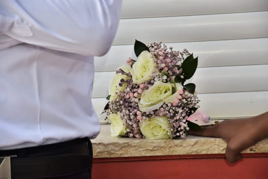 Man groom with white shirt, wedding bouquet of fresh white and pink flowers, hand of the girl of the bride. Without faces. High quality photo