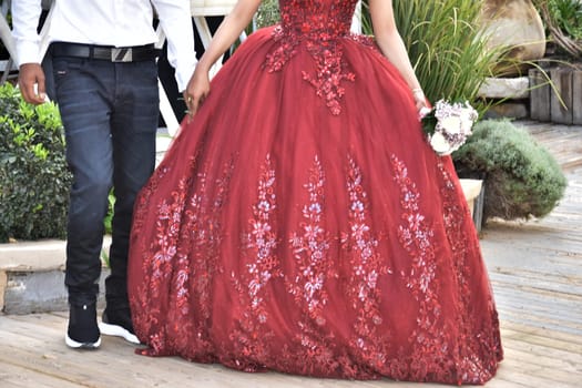 Newlyweds on the street, the bride in a scarlet dress, the groom in a white shirt, no faces. High quality photo