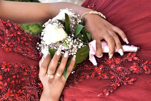 Hand of the bride girl with a wedding bouquet of white and pink flowers on a red dress. High quality photo