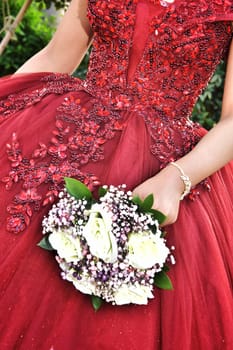 Beautiful red dress of the bride with a wedding bouquet of flowers in her hand, no face, clothes. High quality photo
