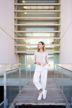 Middle aged woman near an office building wearing casual clothes carrying an eco-friendly ecological metal water bottle. Caucasian female in urban background.