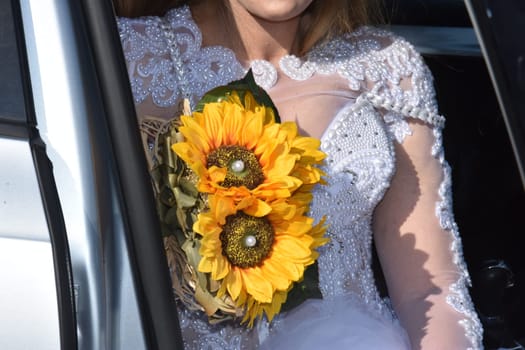 bride in white with a bouquet of yellow sunflower flowers. High quality photo