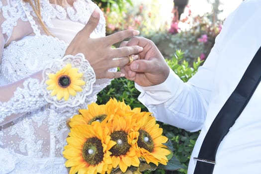 the groom's hands and nevsta with a bouquet of yellow flowers, a gold wedding ring. High quality photo