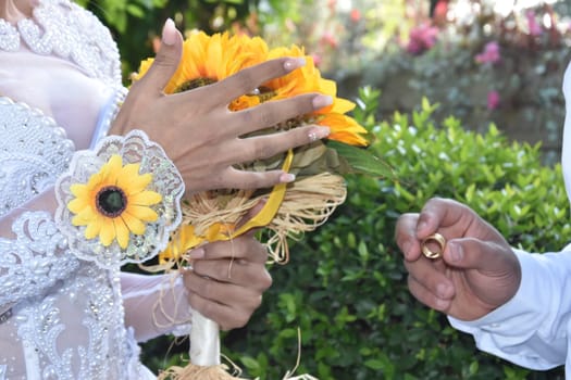 the groom's hands and nevsta with a bouquet of yellow flowers, a gold wedding ring. High quality photo