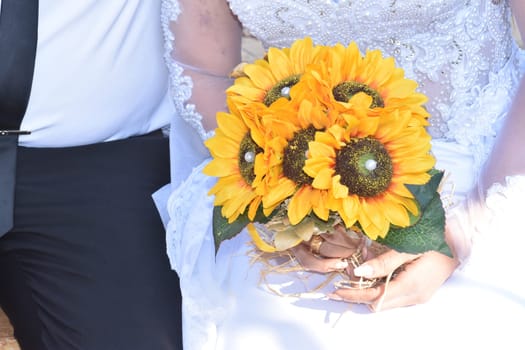 Newlyweds bride and groom in white with a bouquet of yellow sunflowers flowers. High quality photo