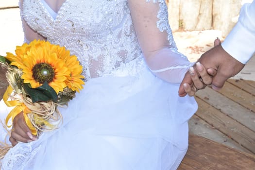 hands of newlyweds with gold wedding rings, yellow flowers. High quality photo