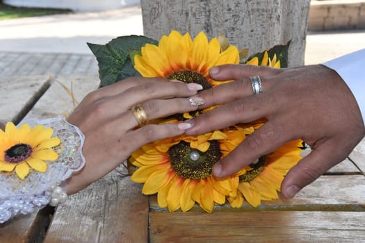 hands of newlyweds with gold wedding rings, yellow flowers. High quality photo