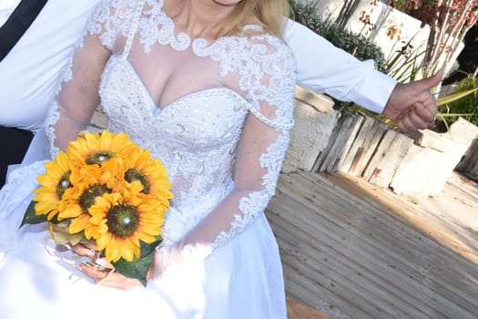 A bride in a white dress with lush breasts, a bouquet of yellow sunflowers,. No face. High quality photo