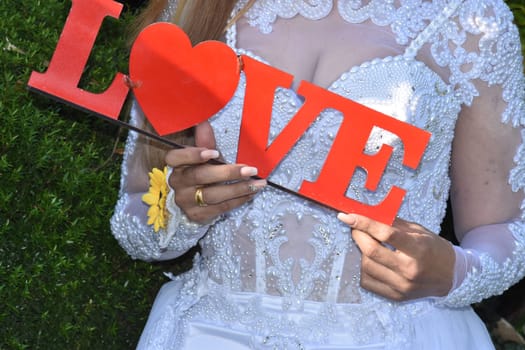 bride in white wedding dress holding red word love with heart. High quality photo