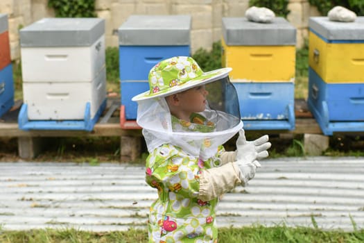 A beekeeper child in apiary in a protective suit