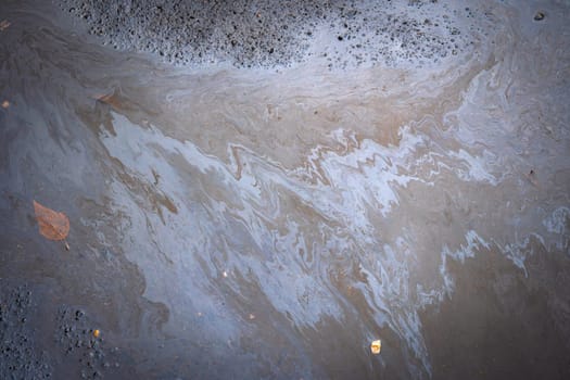 Dirty multi-colored stain from engine oil on asphalt. Environmental pollution concept.
