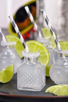 Classic alcoholic cocktail Margarita. Served in mini bottles with salt and lime. An original idea for a buffet event.