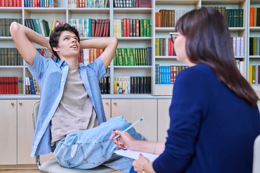 Mature female college counselor, social worker talking with student young male, meeting in library office. Youth mental health, psychology, psychotherapy, help, consultation, mentorship concept