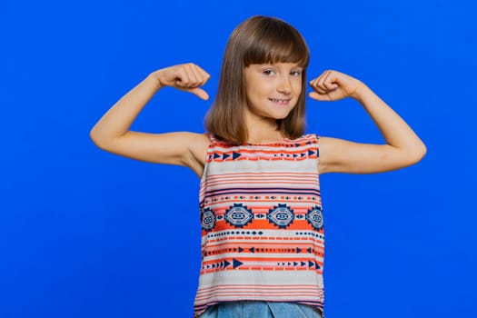 I am strong and healthy. Young cute girl showing biceps and looking confident feeling power strength to fight for rights, energy to gain success win. Preteen brunette child kid on blue background