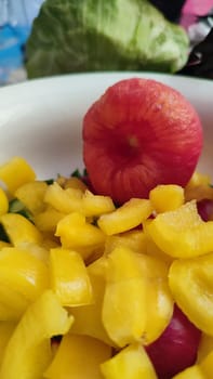 fresh salad of yellow sweet peppers and tomato, vegetables food in a white bowl products, red-yellow background. High quality photo