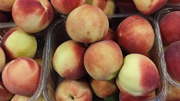 fresh peaches fruits, food in the grocery store, red-yellow background. High quality photo