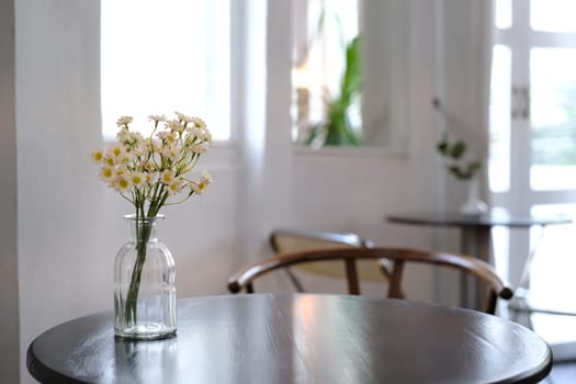 Beautiful bouquet of daisies in glass vases on wooden table at cafe. Interior and decoration concept.