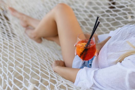 woman with cocktail relaxed in hammock.