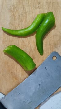 green fresh hot peppers on a kitchen board, a hatchet for cutting vegetables, food. High quality photo