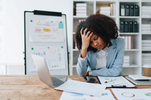 Burnout American African business woman in stress works with many paperwork document, migraine attack, Freelance, work at office.