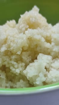 boiled couscous porridge in a green deep plate with a spoon, homemade food. High quality photo