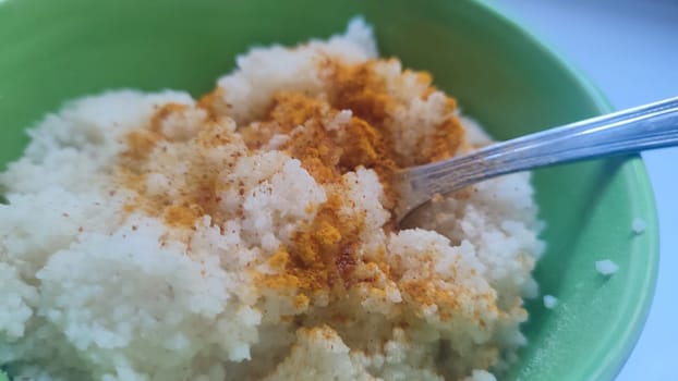 boiled couscous porridge in a green deep plate with a spoon, homemade food. High quality photo