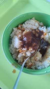 boiled couscous porridge in a green deep plate with a spoon, homemade food. High quality photo