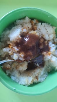 boiled couscous porridge in a green deep plate with a spoon, homemade food. High quality photo