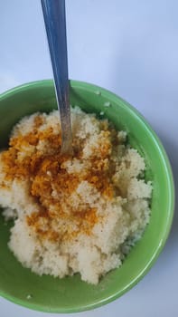 boiled couscous porridge in a green deep plate with a spoon, homemade food. High quality photo