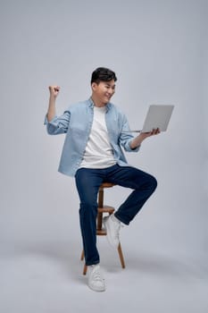 Man using laptop computer and sitting on chair and hands up raised arms from happiness