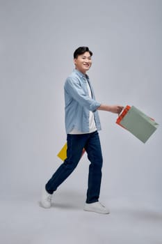 Young positive man hold bags from shopping store advert satisfied