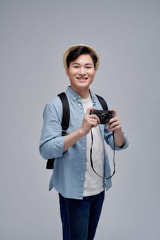 Portrait of smiling young male Asian tourist carrying backpack ready to travel