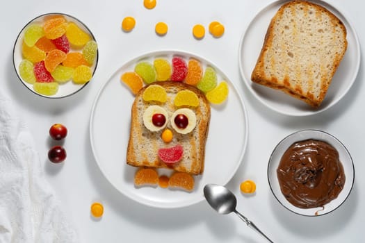 Cute sweet sandwich for kids with toast bread, chocolate spread, marmalade and fresh fruit.