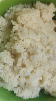 boiled couscous porridge in a green deep plate with a spoon, homemade food. High quality photo