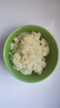 boiled couscous porridge in a green deep plate with a spoon, homemade food. High quality photo