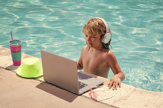 Child working with laptop on summer vacation holidays. Little freelancer using computer, remote working in swimming pool. Summer online technology