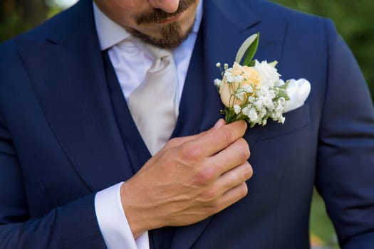 Elegant wedding boutonniere on the groom's suit. Soft focus. No face.